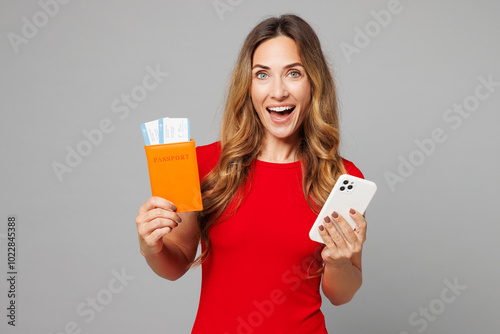 Traveler woman wear red casual clothes hold passport ticket, mobile cell phone isolated on plain grey background studio Tourist travel abroad in free time rest getaway Air flight trip journey concept #1022845388