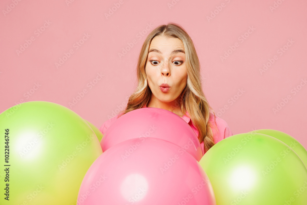 Close up young shocked surprised excited astonished fun woman celebrating birthday holiday looking at bunch of colorful air balloons isolated on plain pastel light pink background. Lifestyle concept. Close up young shocked surprised excited astonished fun woman celebrating birthday holiday looking at bunch of colorful air balloons isolated on plain pastel light pink background. Lifestyle concept.