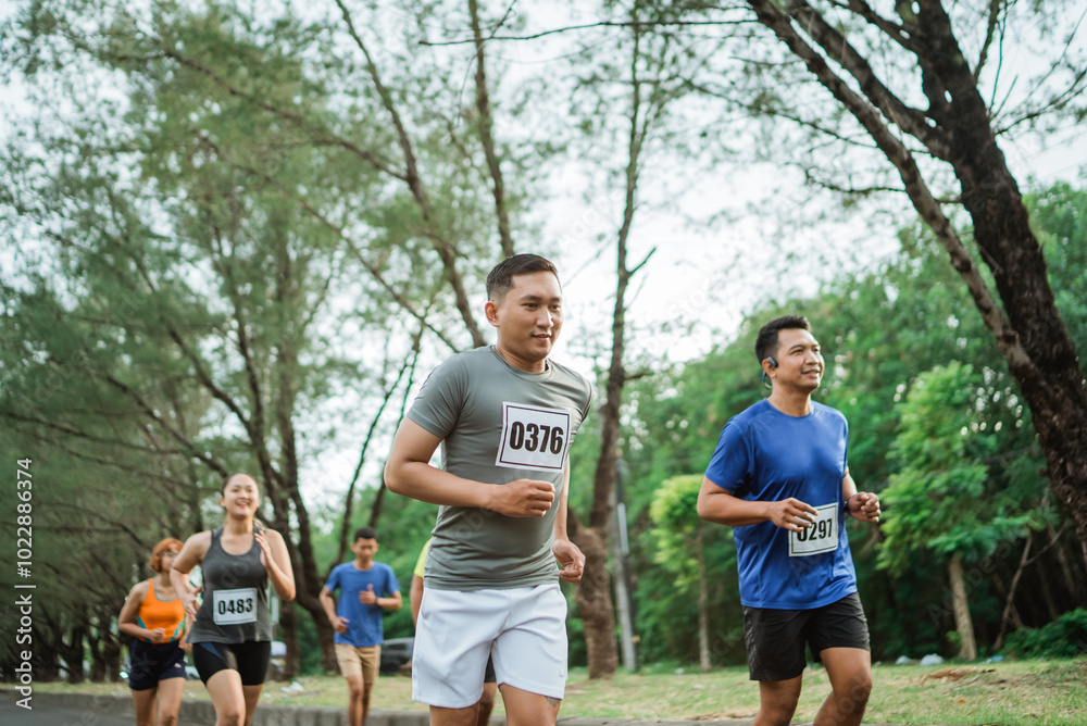 Obraz premium sporty man running through marathon track with other athlete