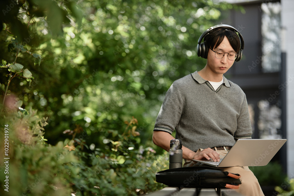 © Seventyfour - Medium shot of Asian male IT developer concentrated on using laptop to write code
