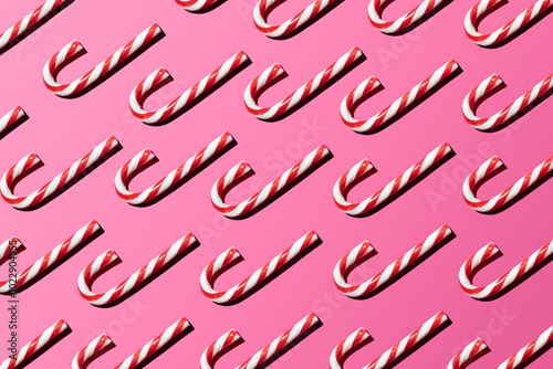 Top view of assorted red and white candy canes on pink background making a pattern