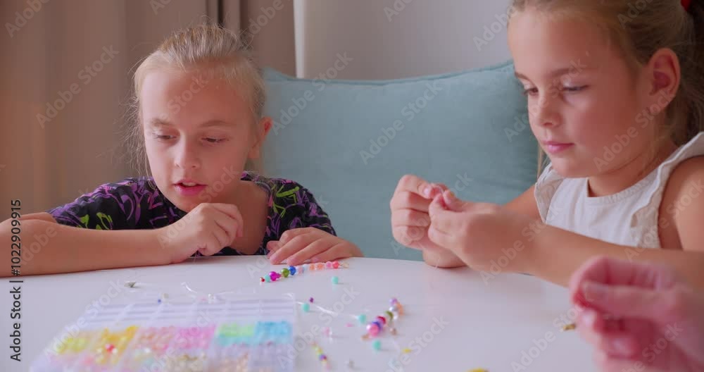 Two Girls Making Beaded Jewelry at Home Crafting Table Two Girls Making Beaded Jewelry at Home Crafting Table