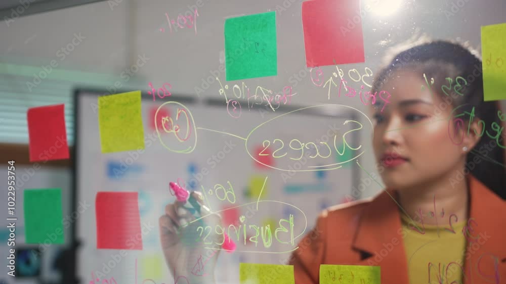 Businesswoman drawing a business strategy on a glass wall in an office, showcasing creativity and planning for success Businesswoman drawing a business strategy on a glass wall in an office, showcasing creativity and planning for success