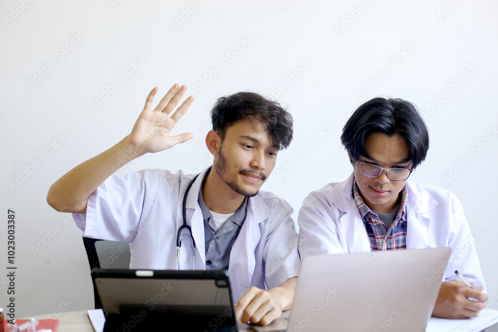 Two Young Asian Medical Students Wearing Uniform Focuses On Studying An Online Class Through Laptop And Ask For The Question Two Young Asian Medical Students Wearing Uniform Focuses On Studying An Online Class Through Laptop And Ask For The Question