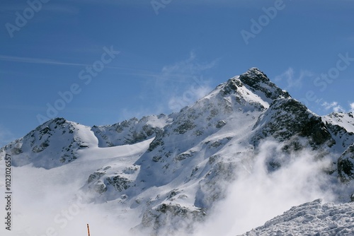 Snowcapped Alpine mountains peaking through clouds in the Three Valleys, France. Breathtaking view from ski resort in French Tarentaise Valley.