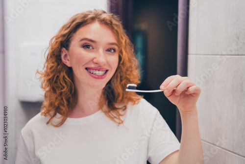 Photo of young woman brushing teeth with toothbrush bathroom interior in the morning indoors