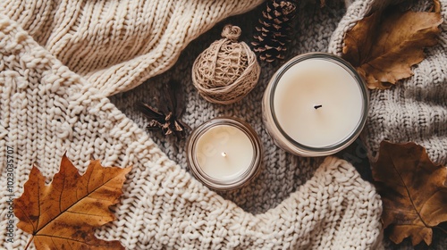 A cozy fall scene with a sweater, candles, and leaves.