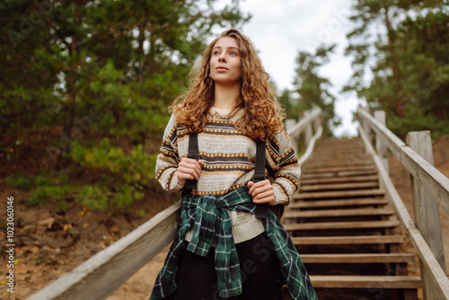 Young tourist woman enjoys the view of the mountain lake. Solitude with nature. Active lifestyle.