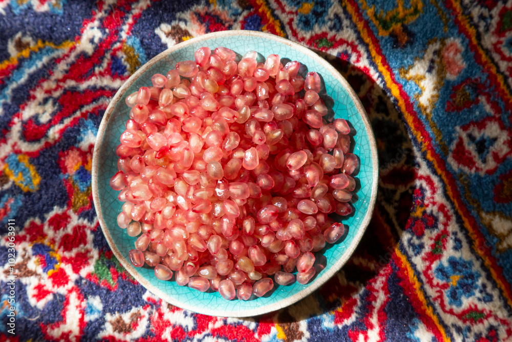 Fresh pomegranate seeds in a bowl on a red carpet shining in the afternoon sunlight. Perfect details. Fresh pomegranate seeds in a bowl on a red carpet shining in the afternoon sunlight. Perfect details.