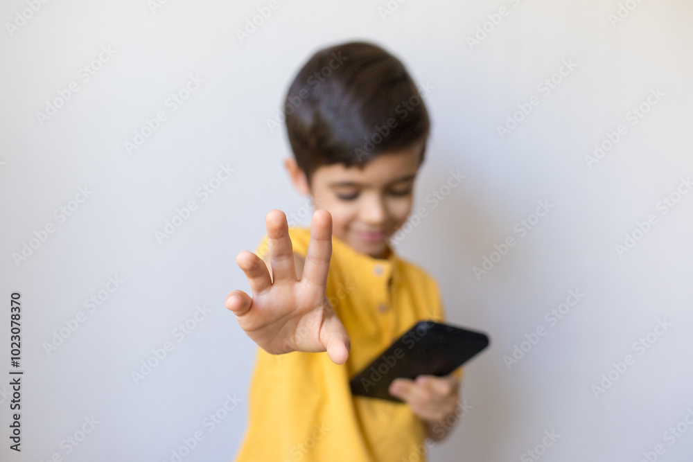 Cute little boy with mobile telephone show stop gesture, close up. Say no, whims, emotions and facial expression. Cute little boy with mobile telephone show stop gesture, close up. Say no, whims, emotions and facial expression.