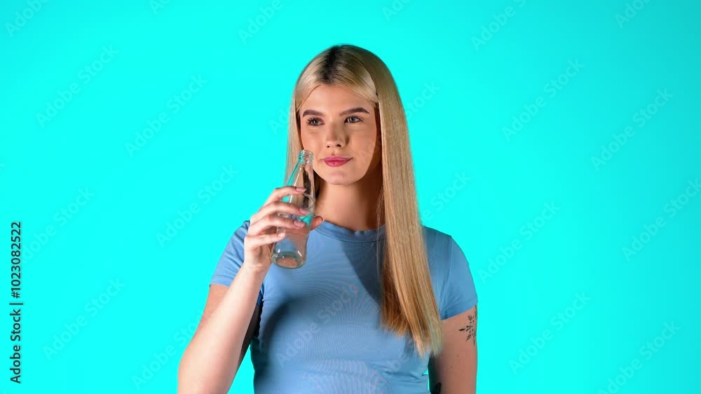 Young Blonde Woman Drinking Water From Glass Bottle, Studio Portrait Young Blonde Woman Drinking Water From Glass Bottle, Studio Portrait