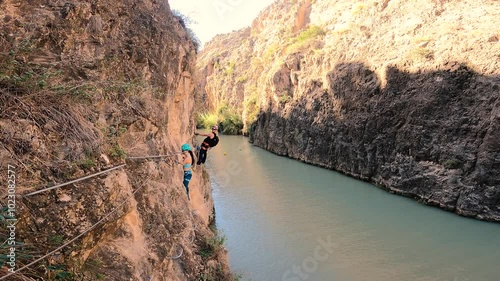 Couple doing via ferrata in Almadenes Canon, Cieza. Risky rock climbing above river in Spain. photo