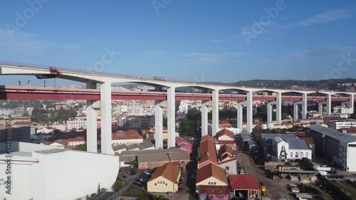 A Ponte 25 de Abril ergue-se majestosamente sobre as águas brilhantes do Rio Tejo, com a sua estrutura vermelha icônica resplandecendo sob o sol intenso. 