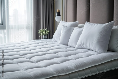 White quilted mattress topper with pillows. Perfect for adding extra comfort and support to your bed.