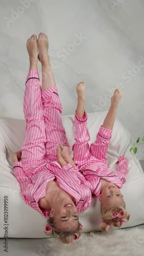 Mother and daughter are lying upside down in pink pajamas. Concept of family entertainment. photo