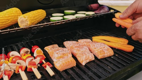 Vegetable skewers, corned salmon fillet on the cob and grilled zucchini slices, with hands placing carrot sticks on the grill.