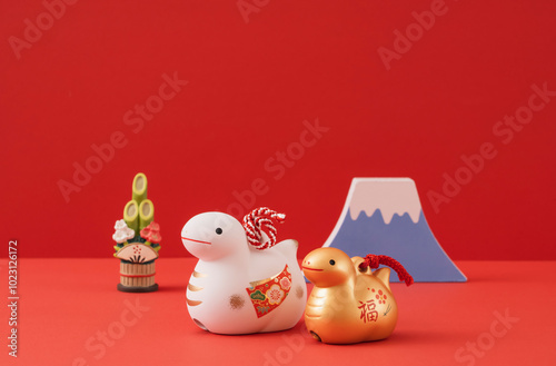 Japanese new year. Zodiac Snake. Snake ornaments and Mt.Fuji and kadomatsu on the red background. 日本のお正月。干支の巳（ヘビ）。赤背景上の巳の置物と富士山と門松。