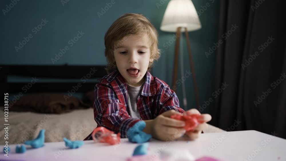 lovely little boy playing with colorful plasticine on his playtable in the bedroom lovely little boy playing with colorful plasticine on his playtable in the bedroom
