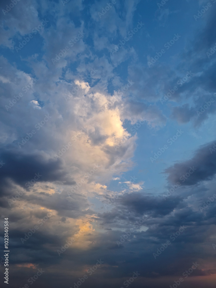 Obraz premium Sky view filled with dramatic clouds during sunset after the storm. Sunlight peeks through, creating a stunning and atmospheric cloudscape scene with vibrant colors and a sense of tranquility