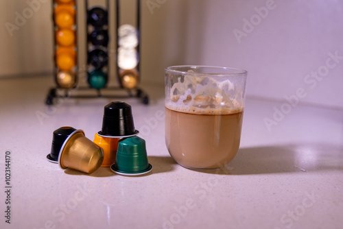Tableau sur toile Coffee cup beside capsules with capsule organizer in the background