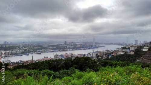 General view of capital of Primorsky Krai and Golden Horn Bay. Ports, docks, berths in water area. Buildings on hills buried in greenery. Vladivostok, Russia, August 13, 2023 photo