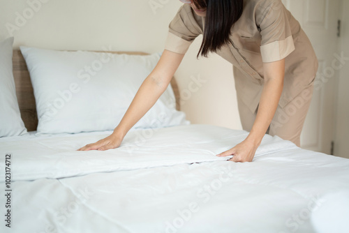 The hotel maid cleans and makes the bed in the hotel room photo