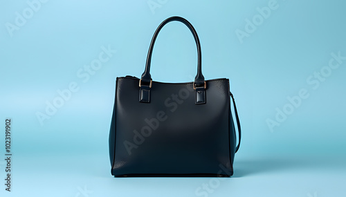 Stylish black women's handbag against a light blue studio backdrop