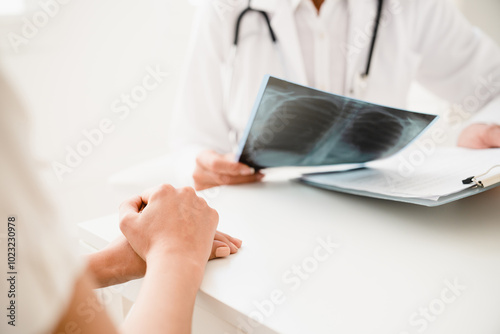 Cropped close up image of doctor talking with patient about health condition, showing x-ray photo, explaining diagnosis at hospital appointment photo