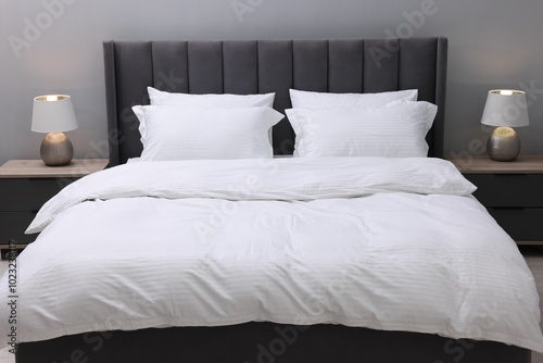 Bed with clean linens and pillows indoors