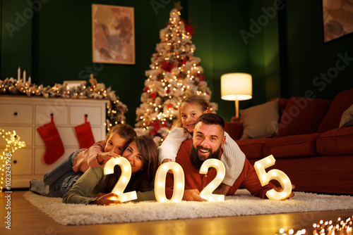 Parents and children holding numbers 2025 while celebrating New Year at home