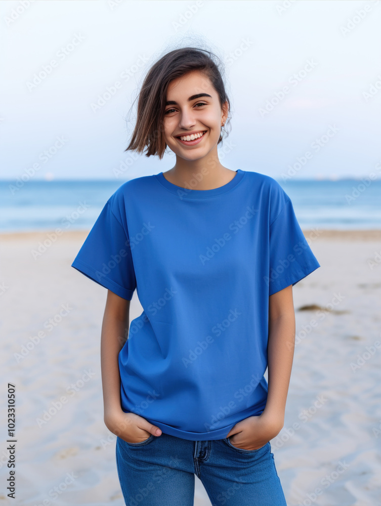 A woman in azure tshirt and jeans smiles on beach