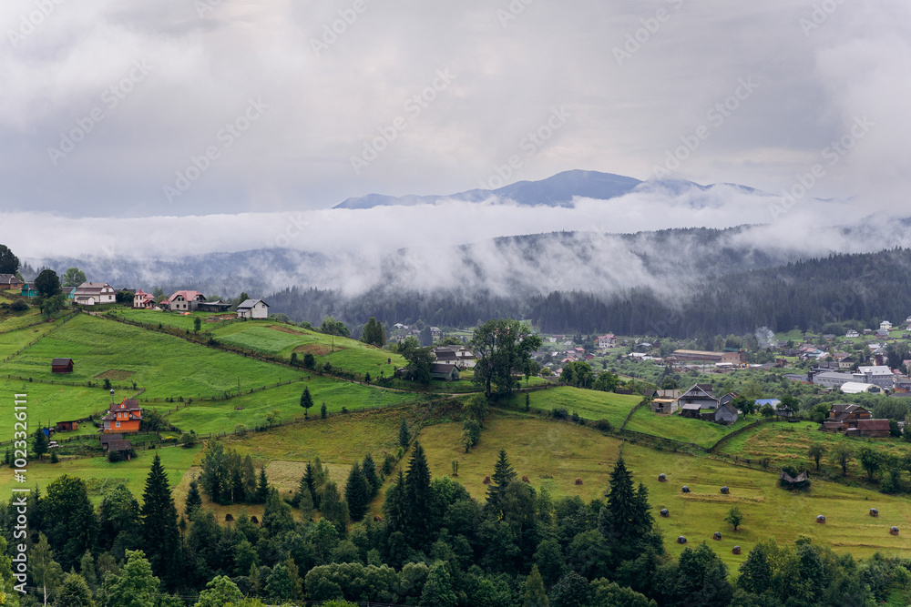 Obraz premium Misty morning in Vorokhta village with scenic view of Carpathian hills and fog-covered mountains