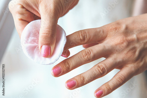 Tableau sur toile close up of female hand with shiny pink nail polish removing polish with cotton