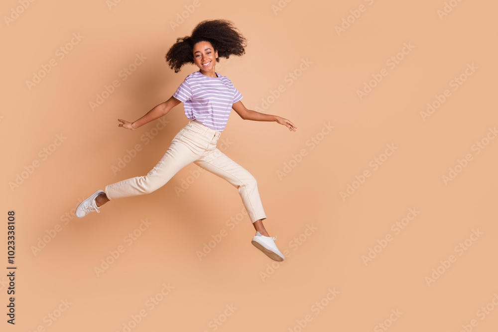 Full length portrait of pretty young woman jump empty space wear t-shirt isolated on beige color background