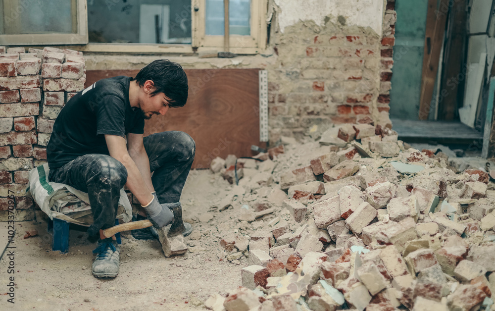 A young man cleans bricks with an axe. A young man cleans bricks with an axe.