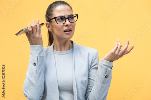 Young worried confused business woman listening voicemail or audio message on her phone while waiting on the city street. Businessperson receiving bad news from office and coworker on her smart phone. photo