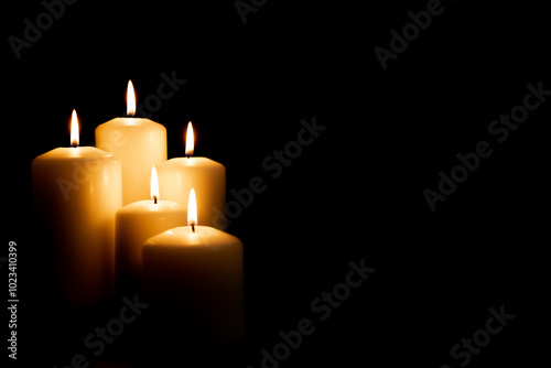 Burning white candles on a black background. Front view.