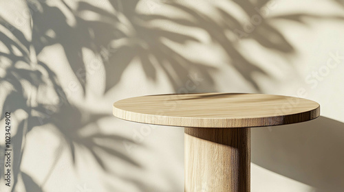 An empty modern round wooden table close-up against a light beige wall with plant shadows photo