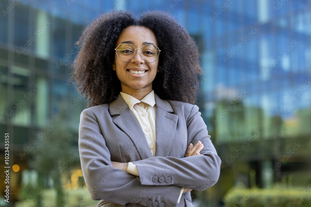 Confident African American business woman in a suit stands with crossed ...