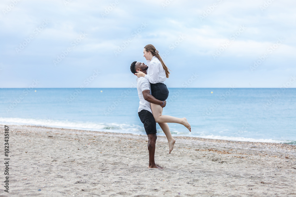A couple enjoying a joyful walk together on the sandy beach of Zapillo in Almeria, Spain during a cloudy afternoon A couple enjoying a joyful walk together on the sandy beach of Zapillo in Almeria, Spain during a cloudy afternoon