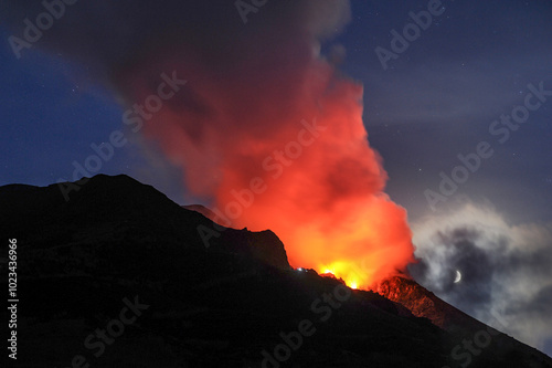 Der Vulkan Stromboli ist umhüllt von einer Wolke, die von unten durch die Krater und von hinten durch den Mond beleuchtet ist. Liparische Inseln. Sizilien