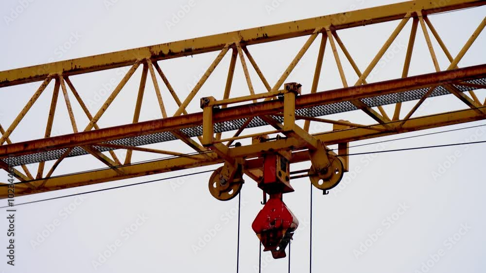 Tall yellow metal structures used for lifting and moving heavy construction. Close up view of crane tower lifting material in building site. Industry Tall yellow metal structures used for lifting and moving heavy construction. Close up view of crane tower lifting material in building site. Industry