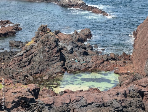 A rocky shoreline with a small water pool in the middle photo