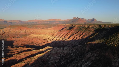 Wallpaper Mural Aerial drone footage over red rock cliffs surrounded by mountains and desert in the background at sunset Torontodigital.ca