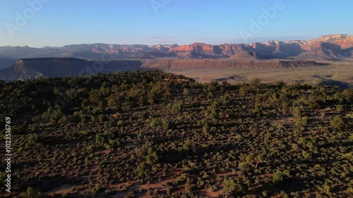 Wallpaper Mural Aerial drone footage over a mesa and bushes surrounded by mountains and red rock desert in the background at sunset Torontodigital.ca