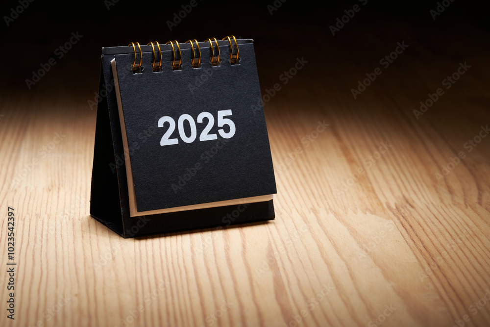 close up of small 2025 desktop calendar on wood table top close up of small 2025 desktop calendar on wood table top