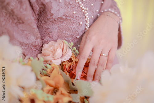 Close Up of woman's hand holding a bouquet of flowers and wearing an engagement ring
