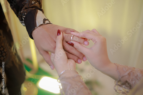 Closeup of woman's hand putting ring on man's hand. Wedding ring exchange and proposal procession