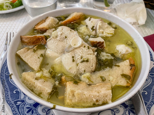 A traditional Portuguese dish featuring sopa de cação ,dogfish soup, served in a rustic restaurant. The bowl is garnished with fresh herbs, showcasing authentic culinary heritage.