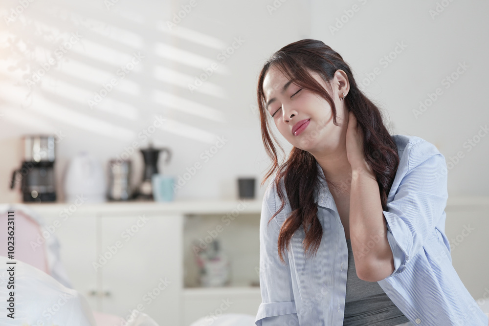 Brunette woman having pain in neck while working. Asian woman using smartphone suffering for cervical pain at home. Brunette woman having pain in neck while working. Asian woman using smartphone suffering for cervical pain at home.